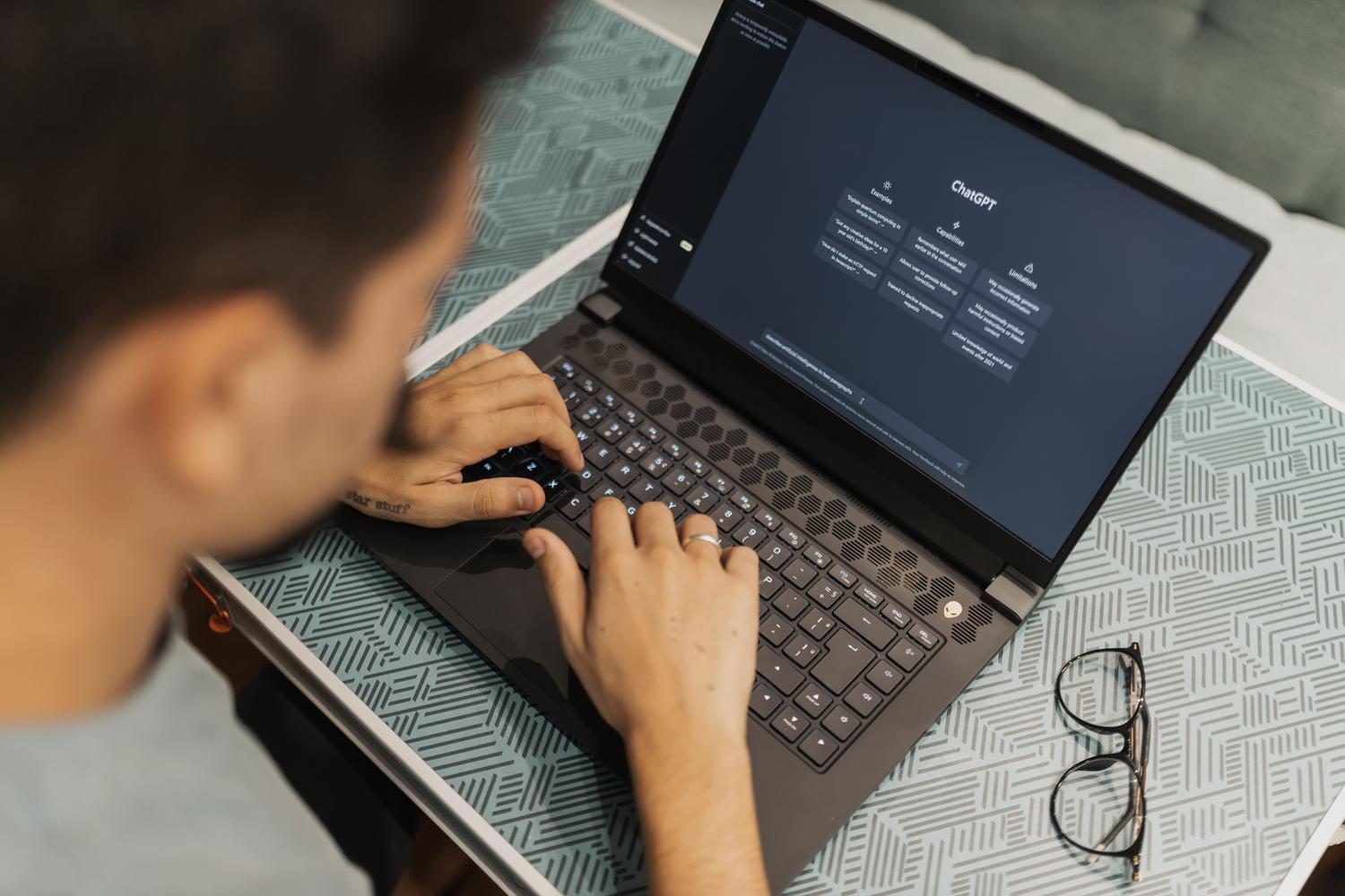 Persona concentrada utilizando un ordenador portátil con software de IA, representando el flujo de trabajo moderno.