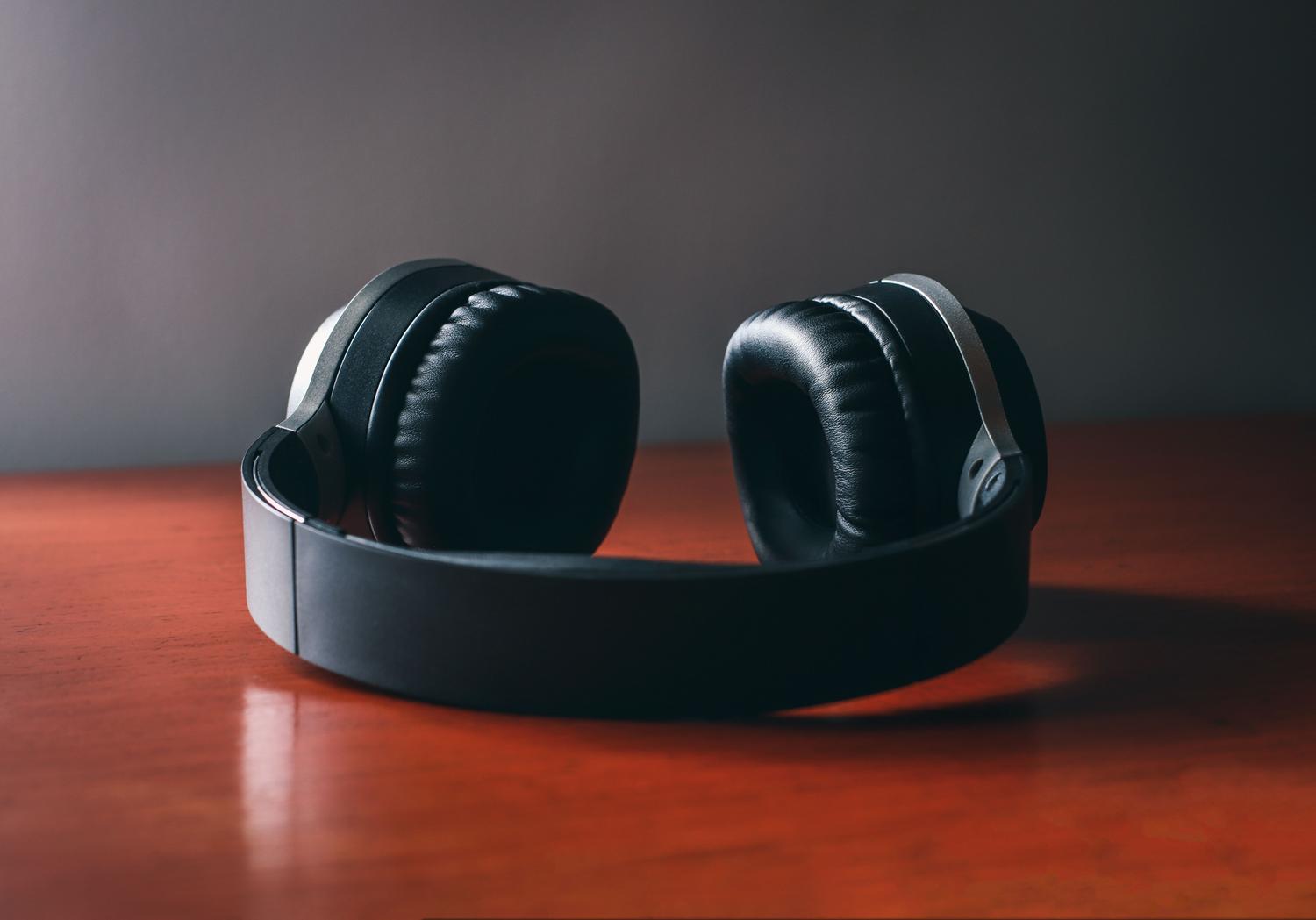 Primer plano de unos auriculares inalámbricos negros sobre una superficie de madera.