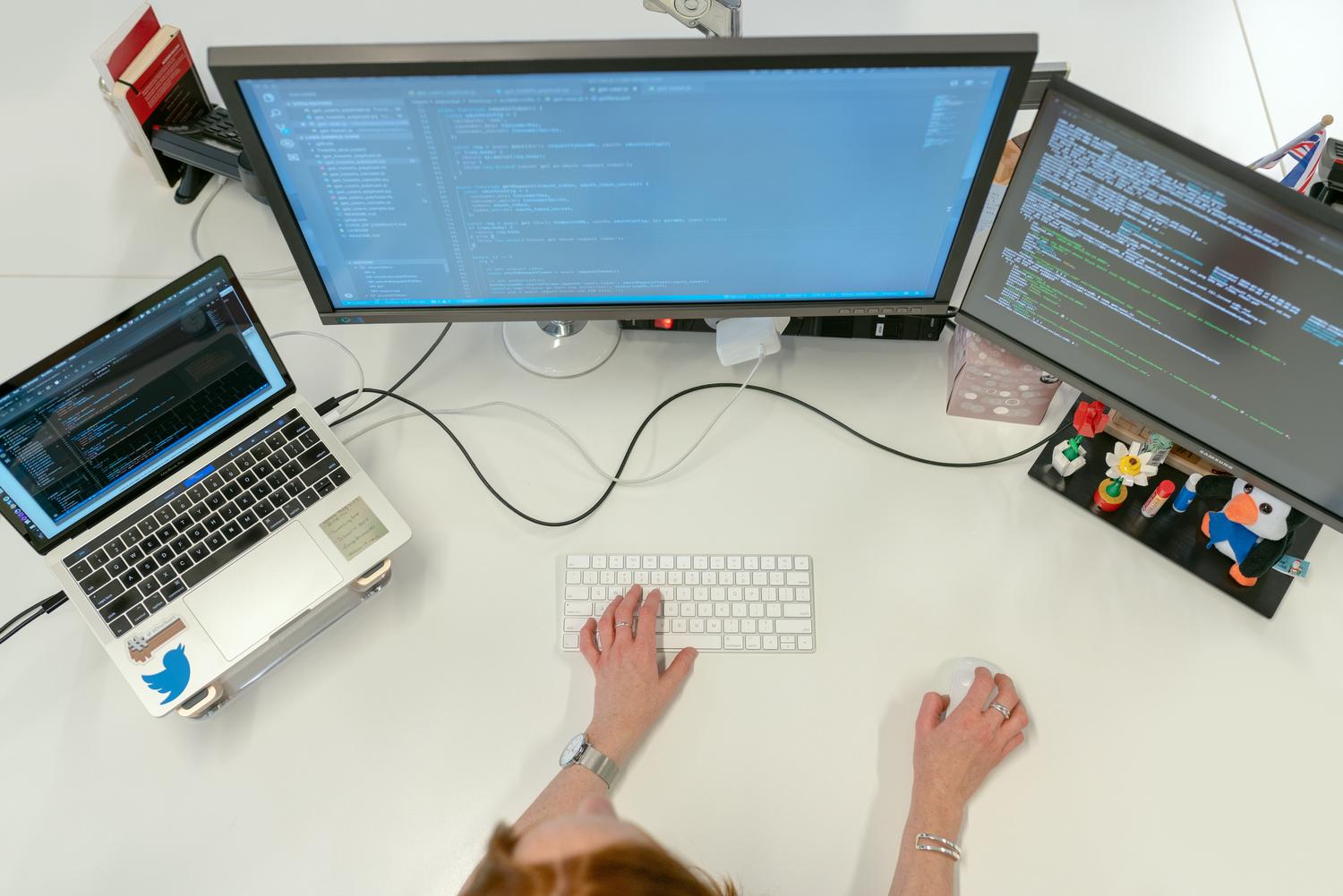Profesional trabajando con múltiples monitores en una oficina, ilustrando el flujo de trabajo avanzado de perfiles como Community Managers o freelancers.