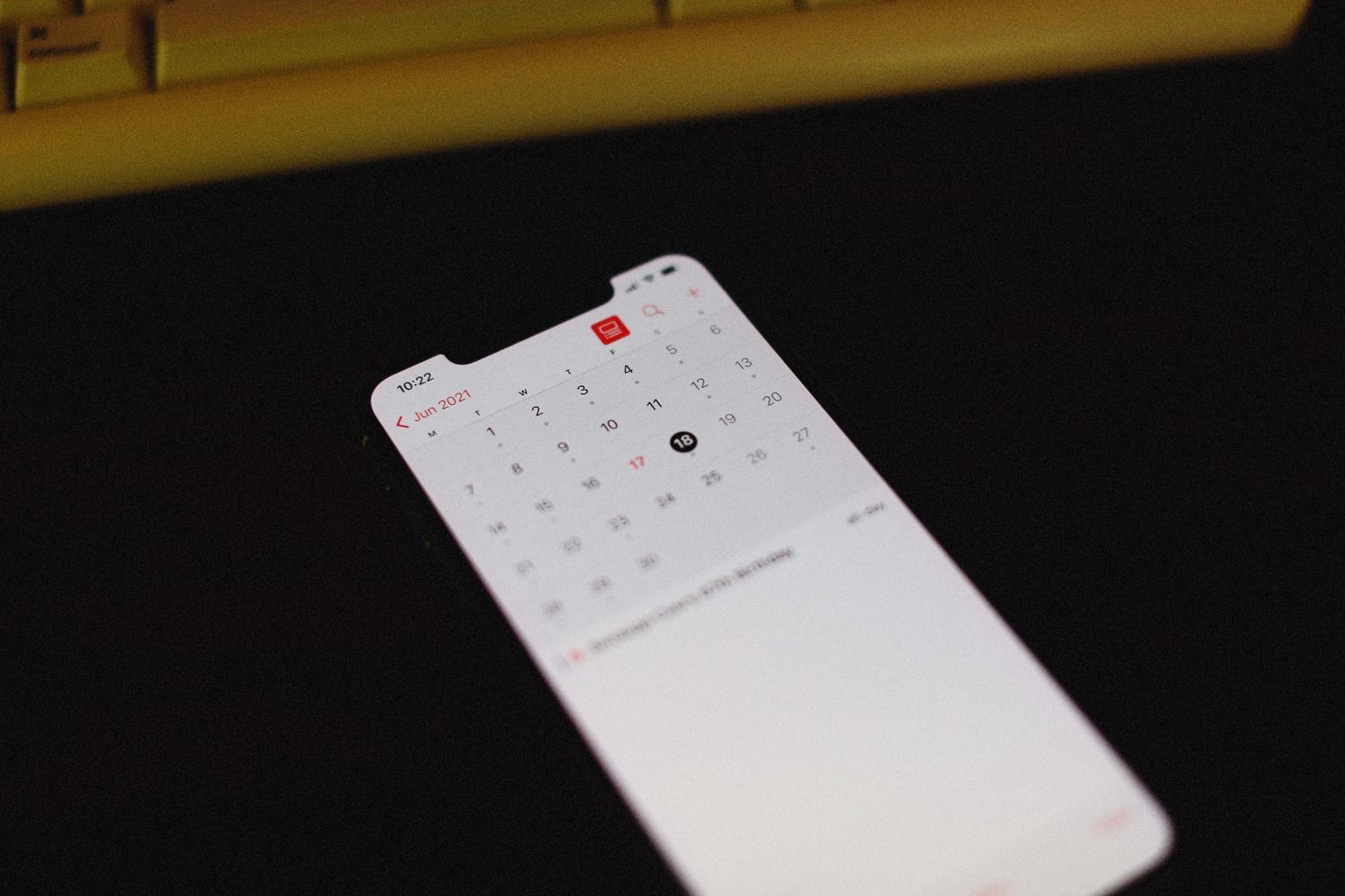 Primer plano de un smartphone con la aplicación de calendario iluminada sobre un fondo oscuro.