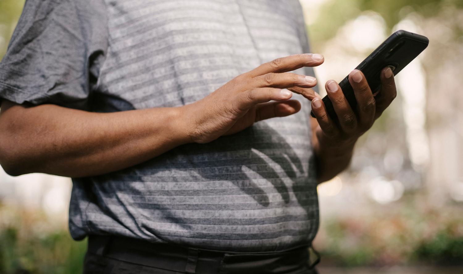 Hombre utilizando su smartphone mientras camina por la ciudad, ilustrando la recepción de información proactiva y contextual.