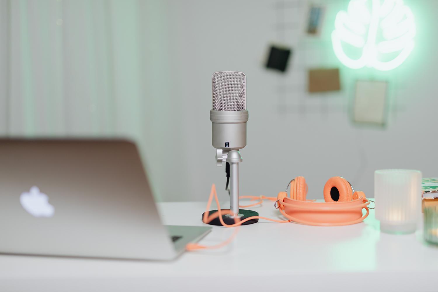 Escritorio moderno con micrófono de condensador, auriculares y portátil, ideal para ilustrar la privacidad del audio en Windows 11.