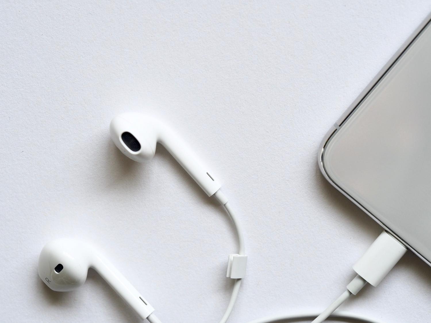 Primer plano de auriculares con cable conectados a un smartphone, representando la antena necesaria para la radio FM.