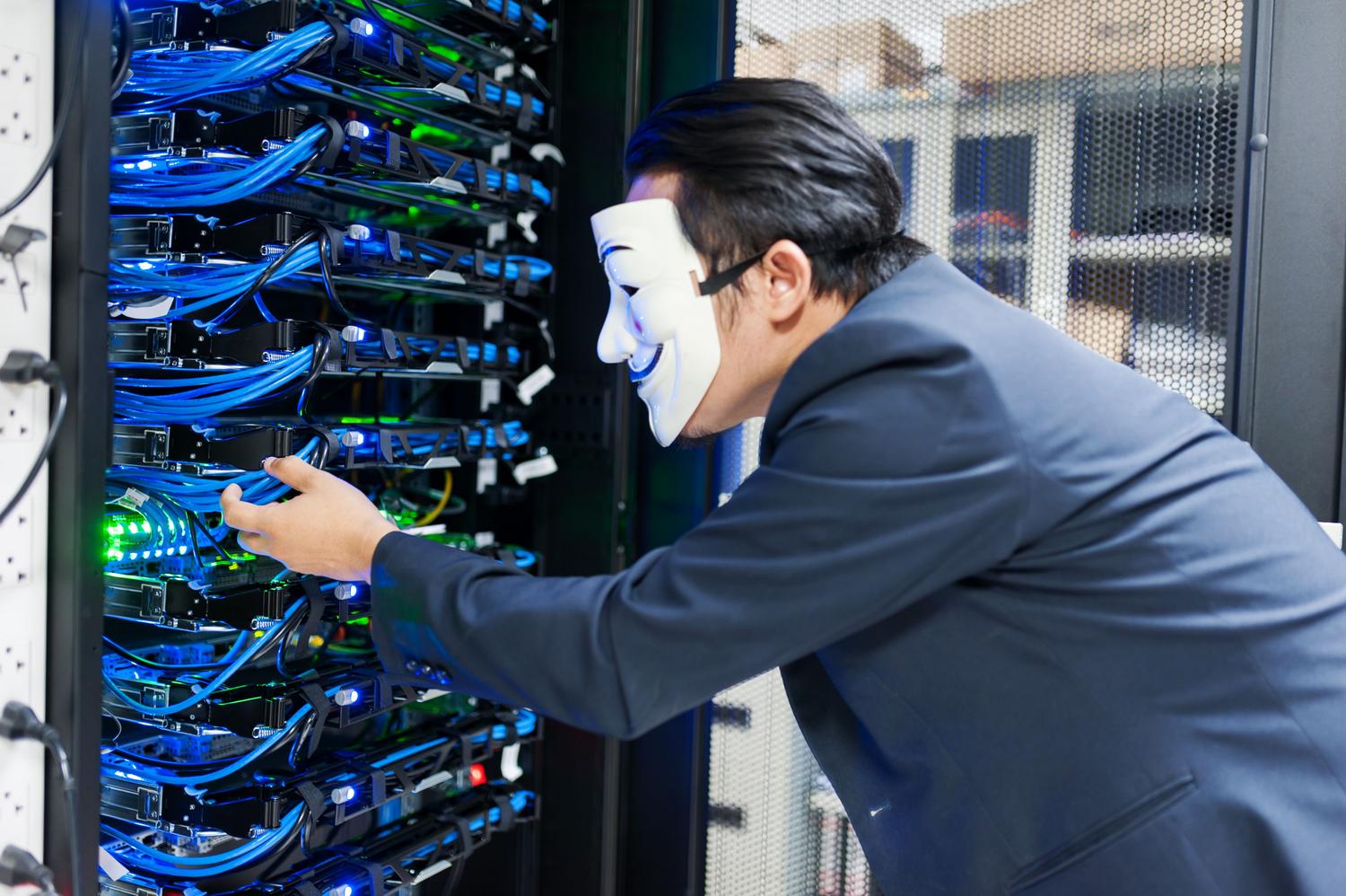Cybersecurity threat concept with a masked figure near servers, highlighting the importance of EDR and malware protection on Linux.
