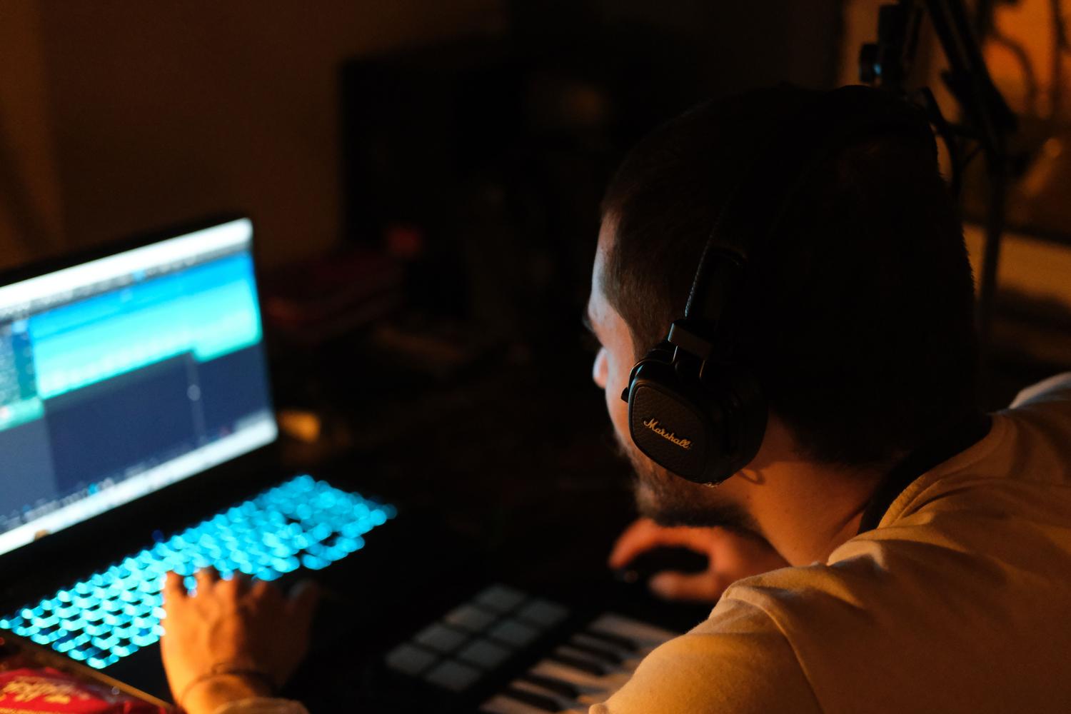 Creador de contenido utilizando auriculares y laptop en un entorno de edición. Creador de contenido utilizando auriculares y laptop en un entorno de edición.