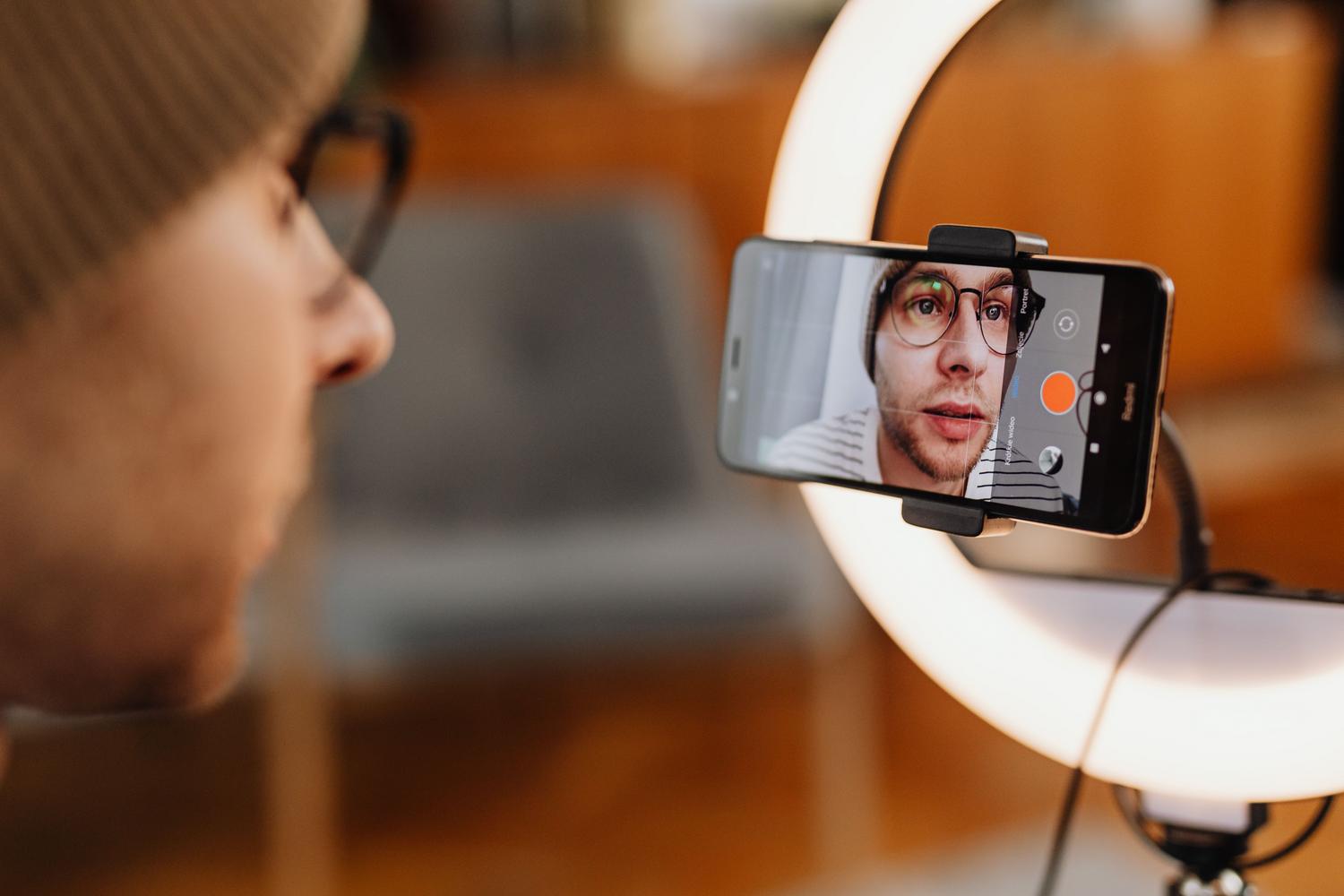 Creador de contenido digital grabando un vídeo con un smartphone y un anillo de luz en un entorno profesional. Creador de contenido digital grabando un vídeo con un smartphone y un anillo de luz en un entorno profesional.