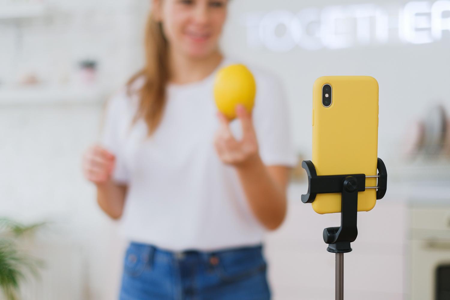 Mujer grabando un tutorial de cocina con su teléfono móvil utilizando un trípode. Mujer grabando un tutorial de cocina con su teléfono móvil utilizando un trípode.