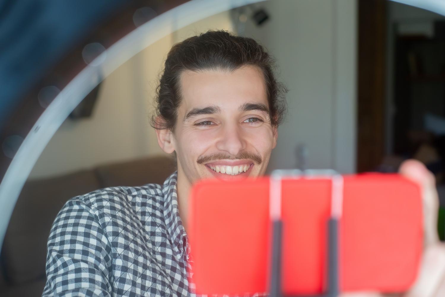 Joven vlogger grabando un vídeo selfie con su móvil y equipo de iluminación profesional. Joven vlogger grabando un vídeo selfie con su móvil y equipo de iluminación profesional.