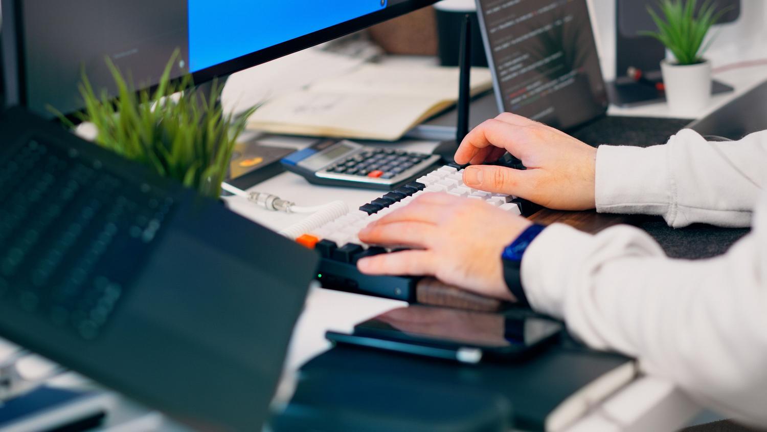 Espacio de trabajo tecnológico moderno con teclado mecánico y monitores, que evoca un entorno de productividad digital y técnica.