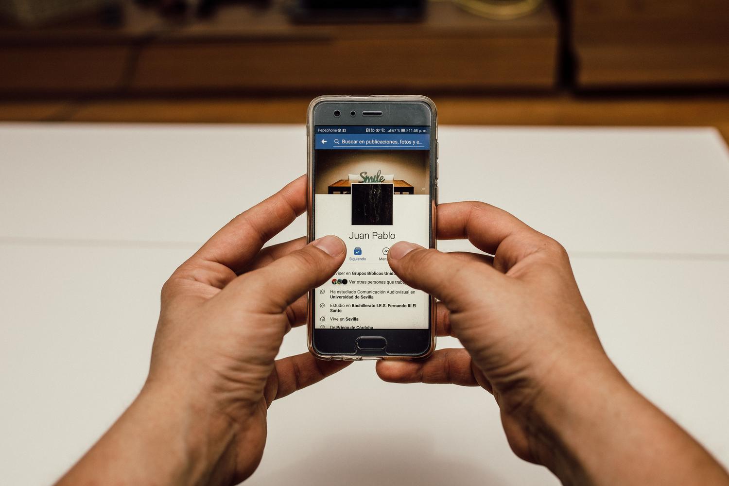 Primer plano de manos navegando por una página web en un smartphone, ilustrando la consulta de contenido web.