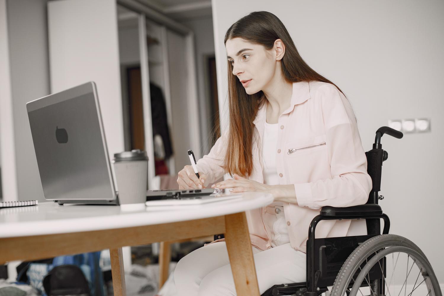 Persona en silla de ruedas trabajando con una laptop, representando la accesibilidad digital y el diseño inclusivo.