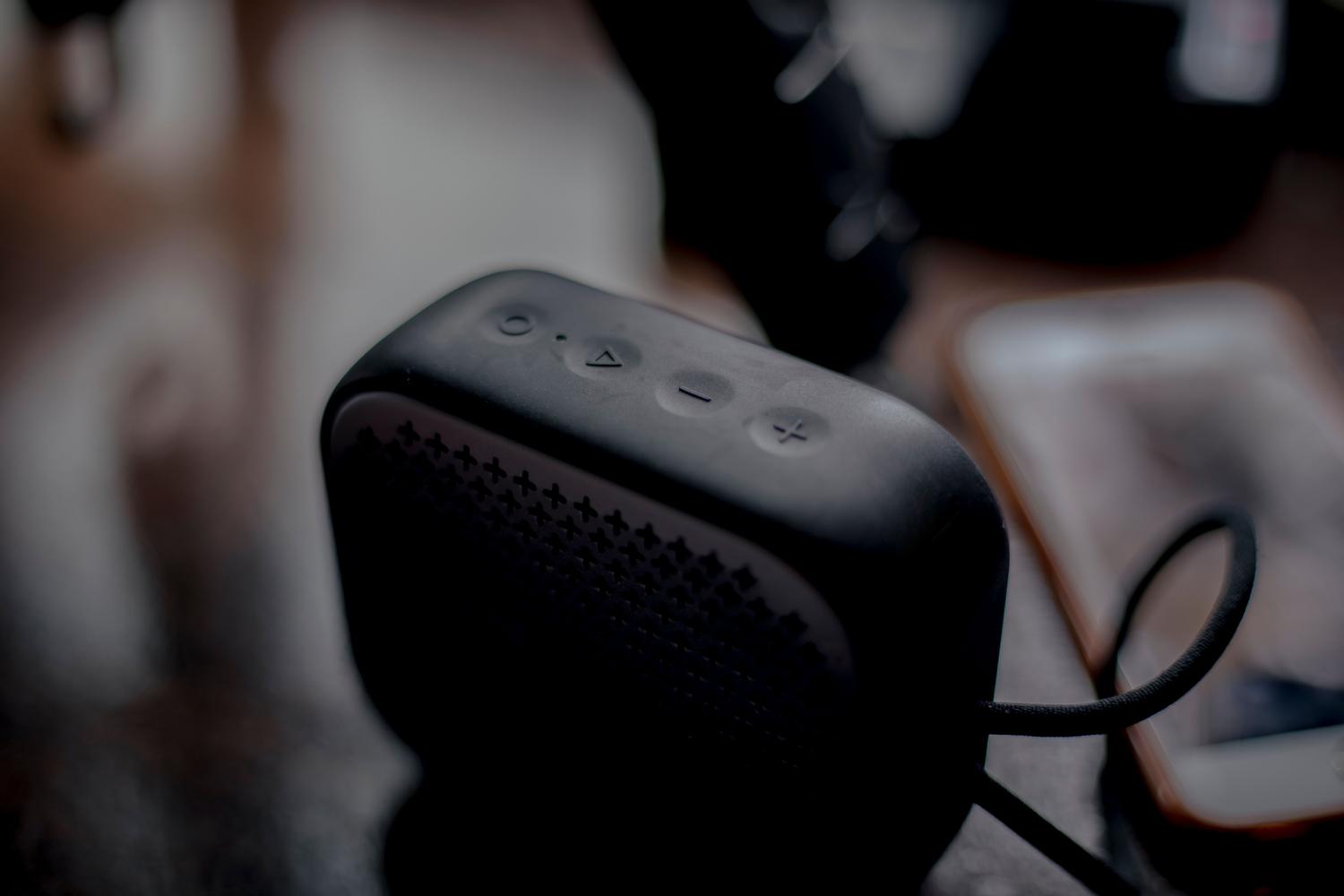 Altavoz Bluetooth portátil junto a un smartphone sobre una mesa de madera