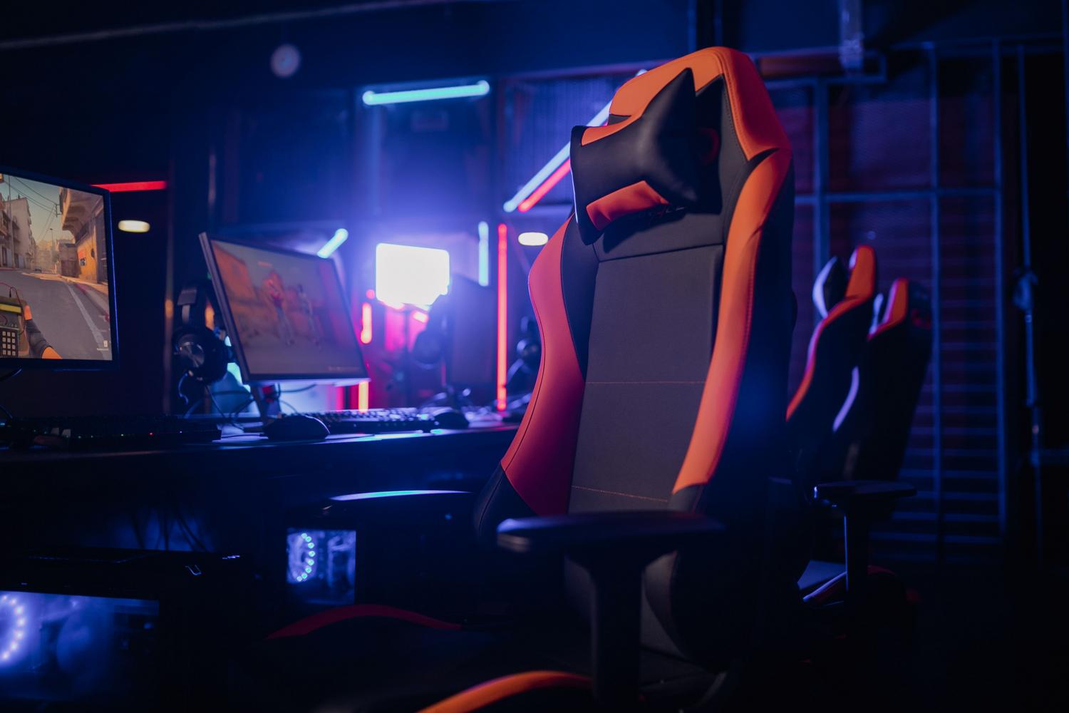 Modern ergonomic gaming chair in front of a PC with ambient neon lighting.
