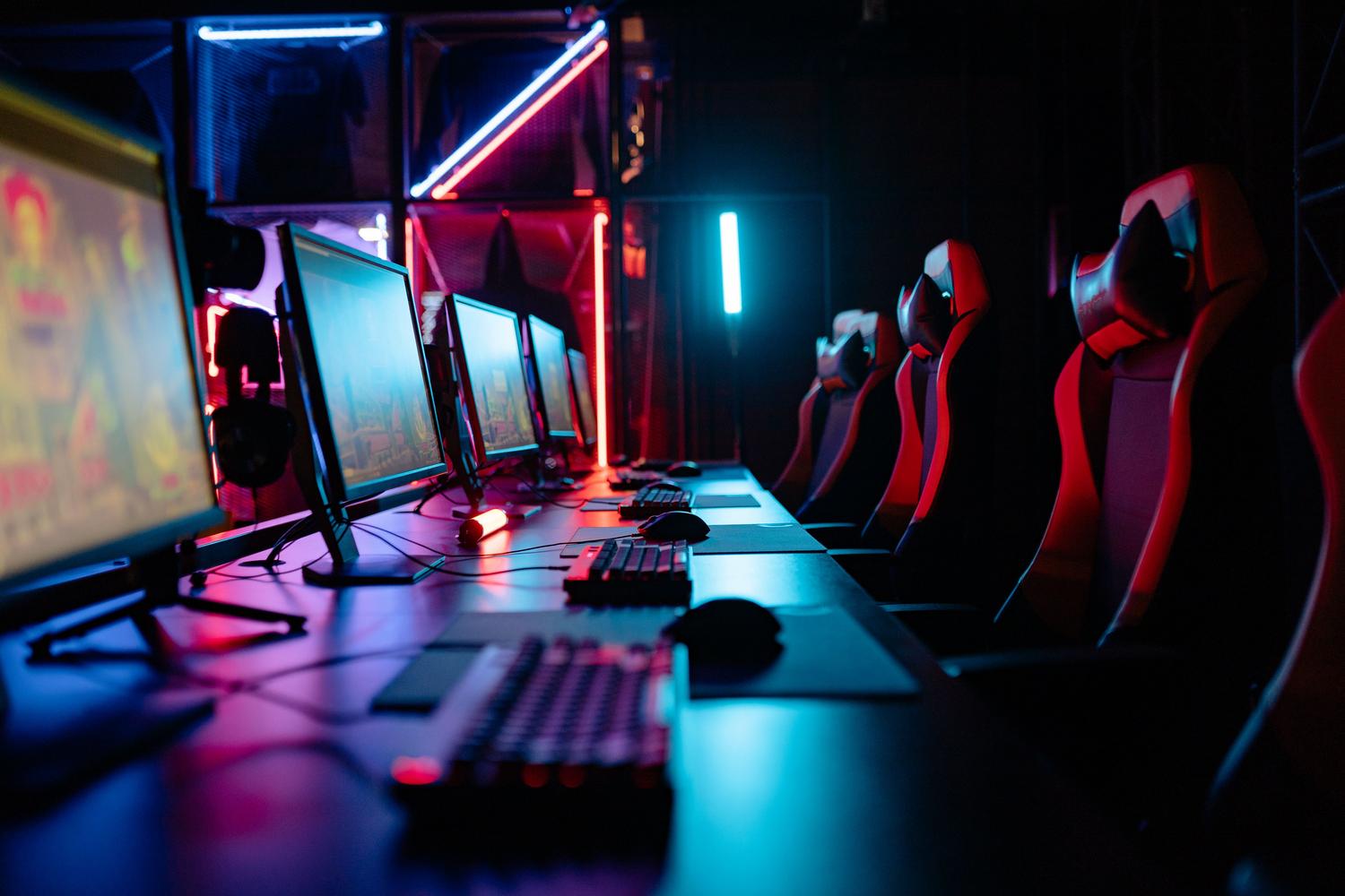 Professional gaming environment with multiple PC setups and neon lights. Professional gaming environment with multiple PC setups and neon lights.