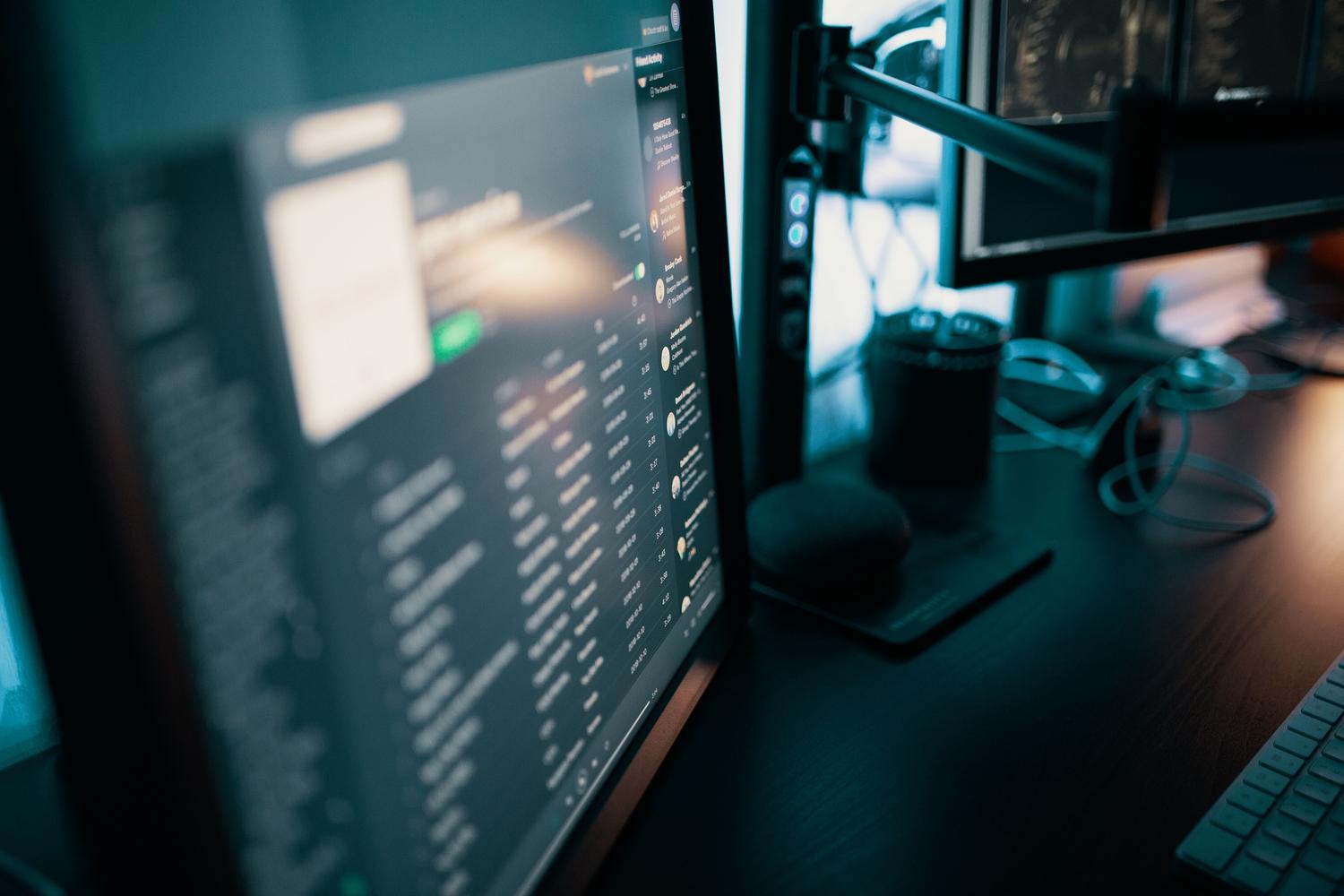 Plano cinematográfico de una configuración de computadora con múltiples monitores centrada en software de productividad en un entorno profesional.