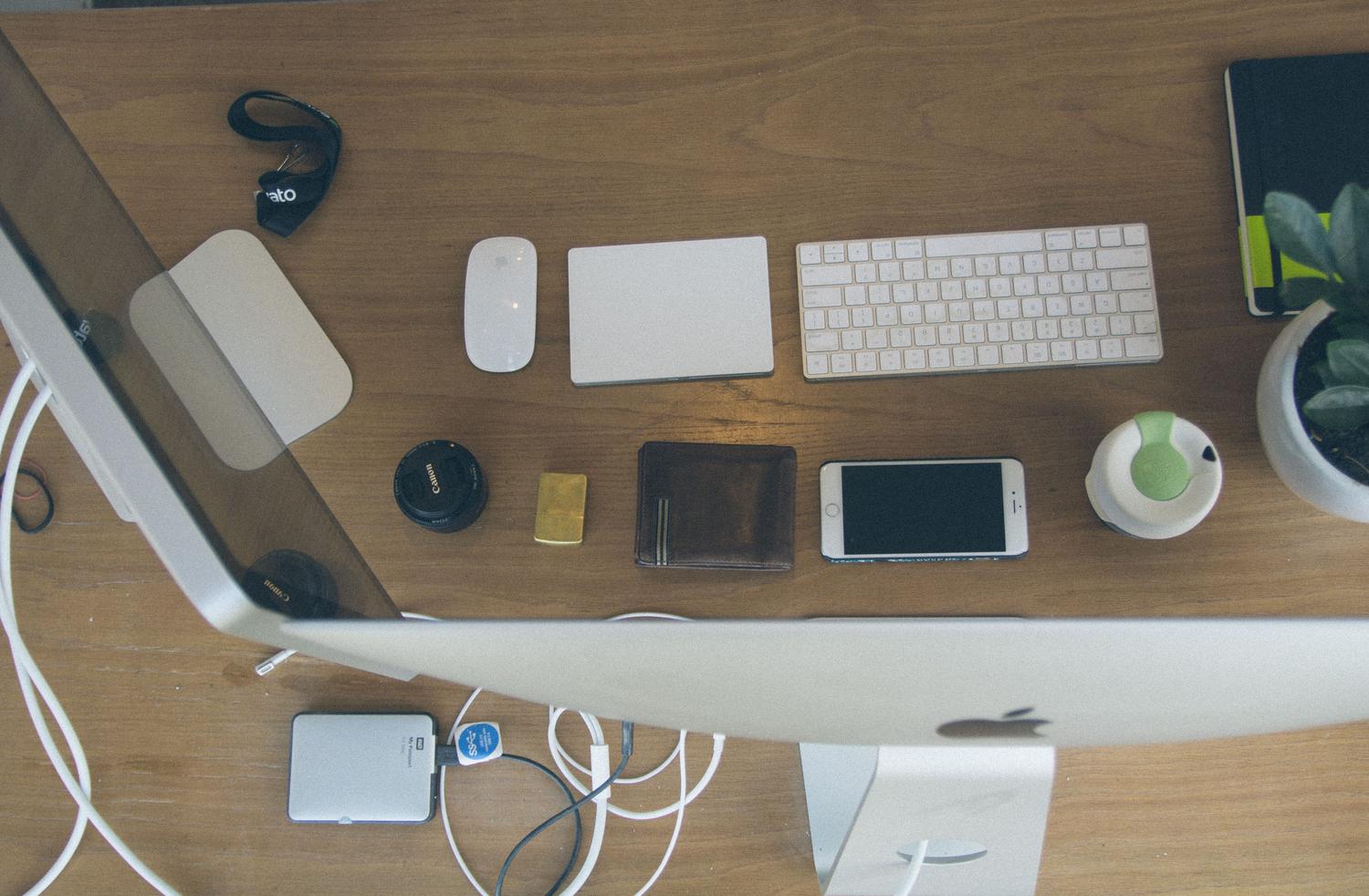 Espacio de trabajo digital limpio y organizado con dispositivos Apple, contrastando el orden con el desorden digital.