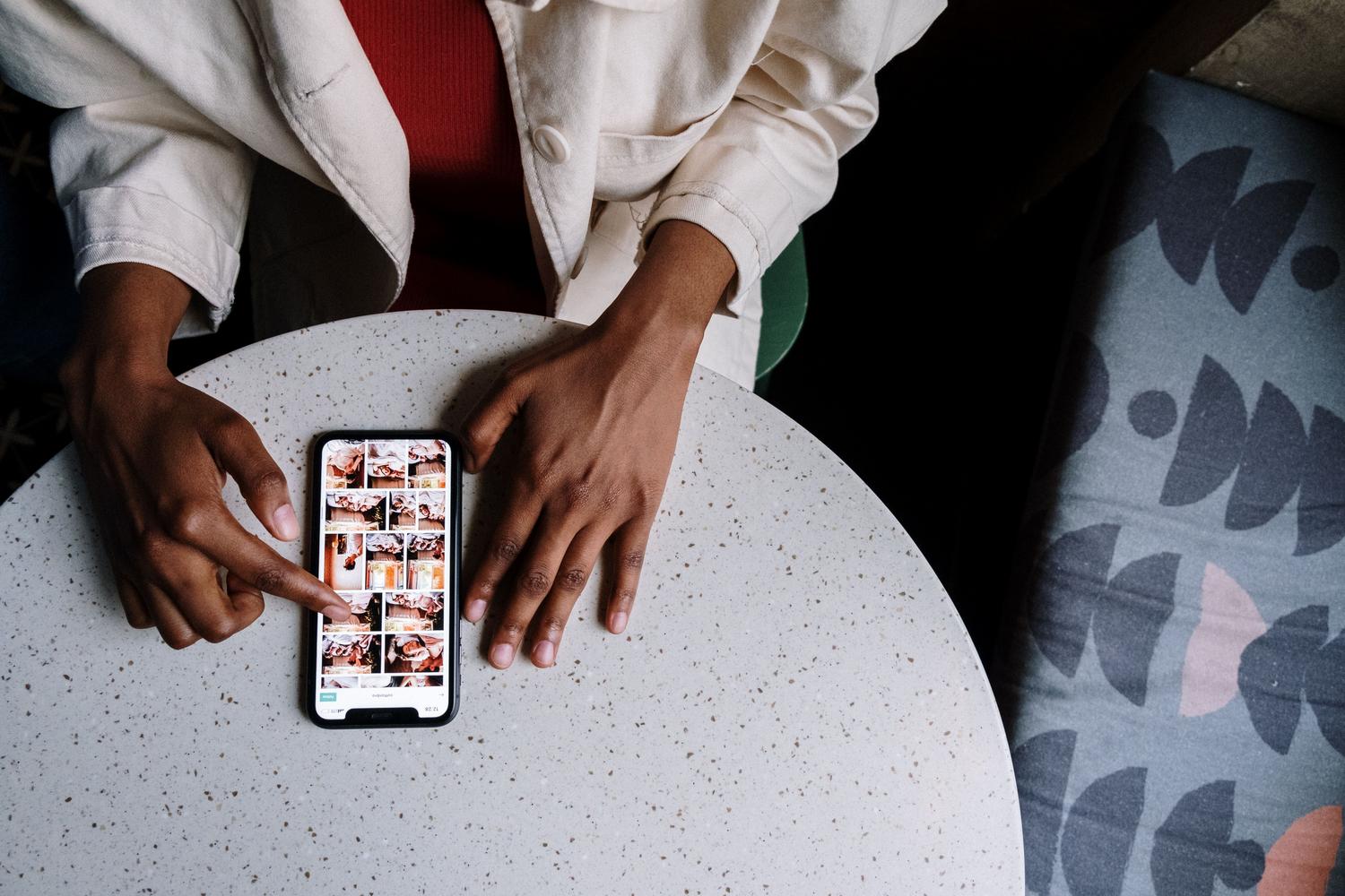 Vista cenital de una persona organizando sus fotografías en un smartphone sobre una mesa.