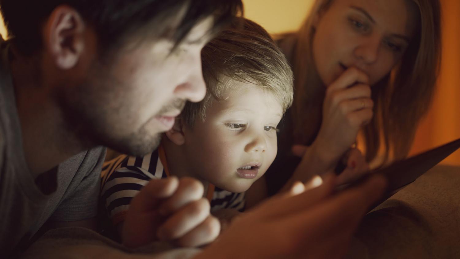 Familia compartiendo momentos mientras miran una tablet, simbolizando el acceso a recuerdos digitales.