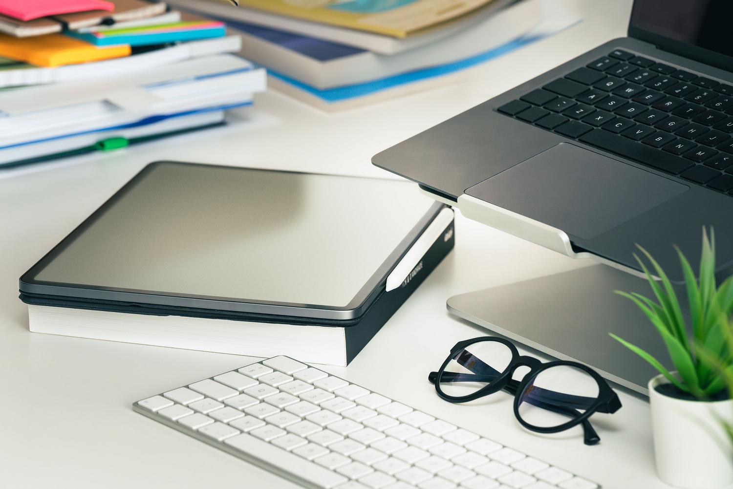 Tableta digital apoyada sobre un cuaderno físico en un escritorio limpio, simbolizando la migración de documentos rígidos a herramientas digitales ágiles.