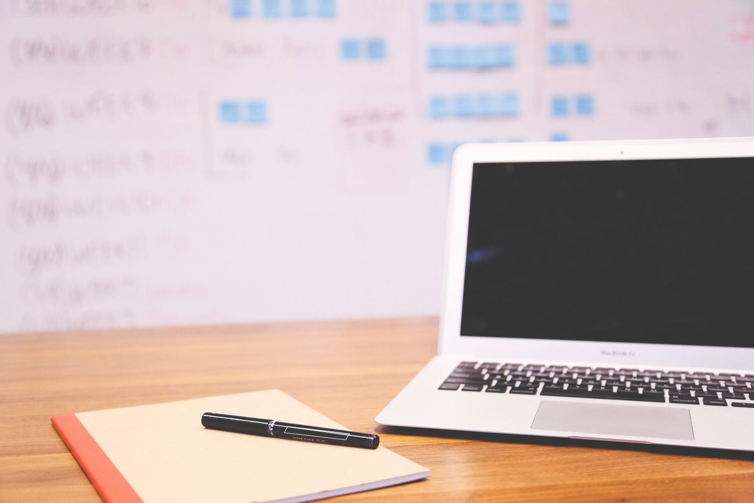 Vista cenital de un espacio de trabajo minimalista con laptop y cuaderno, transmitiendo orden, claridad y enfoque en la organización de contenidos.