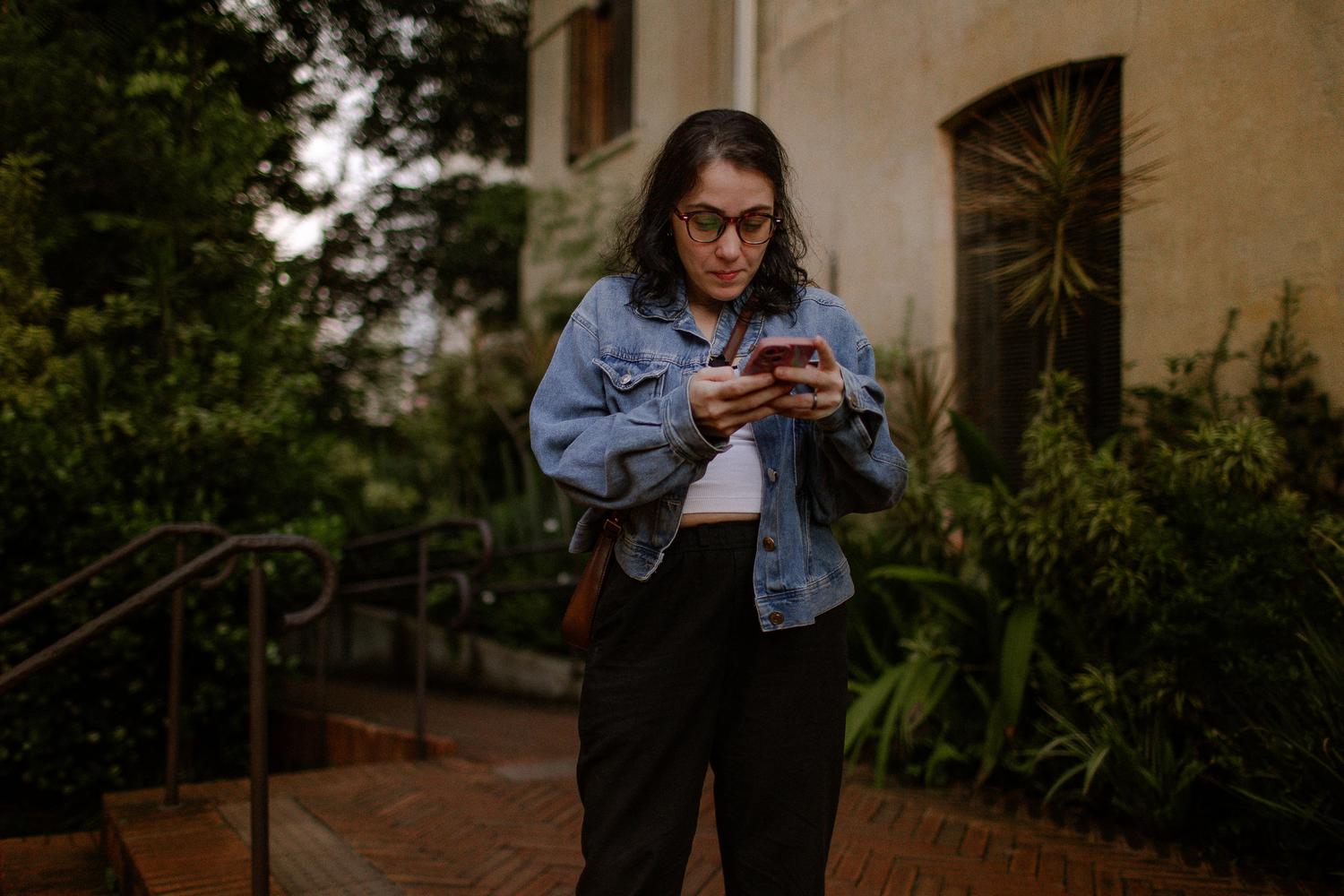 Joven utilizando un smartphone en un entorno exterior natural.