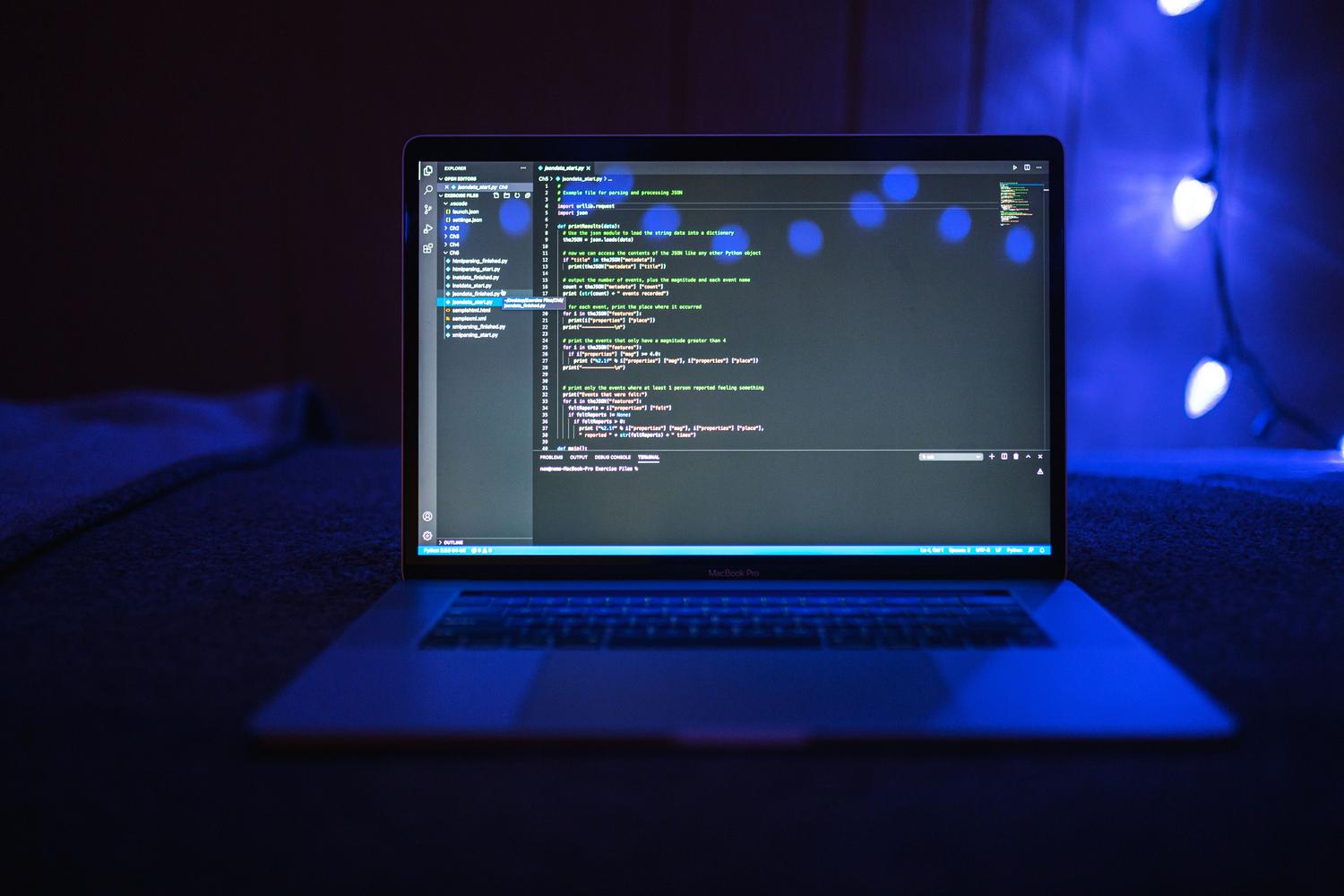 Primer plano de una pantalla de portátil mostrando código de programación con iluminación azul, evocando la esencia del desarrollo de sistemas operativos.
