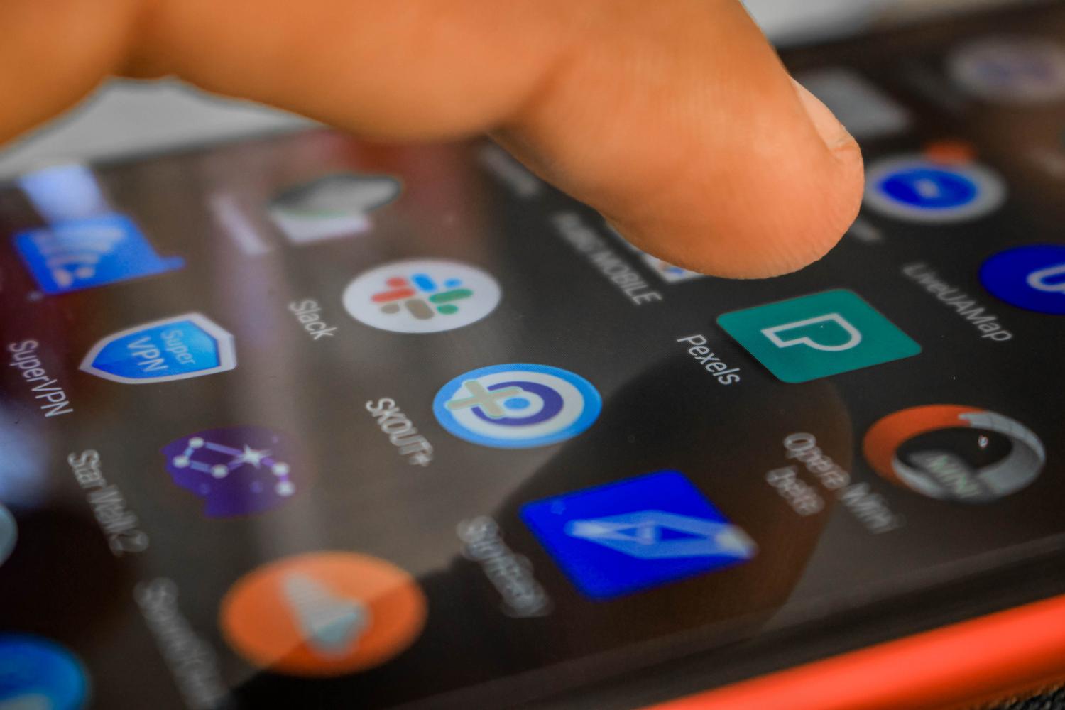 Primer plano de una mano interactuando con la pantalla de un smartphone Android mostrando diversas aplicaciones.