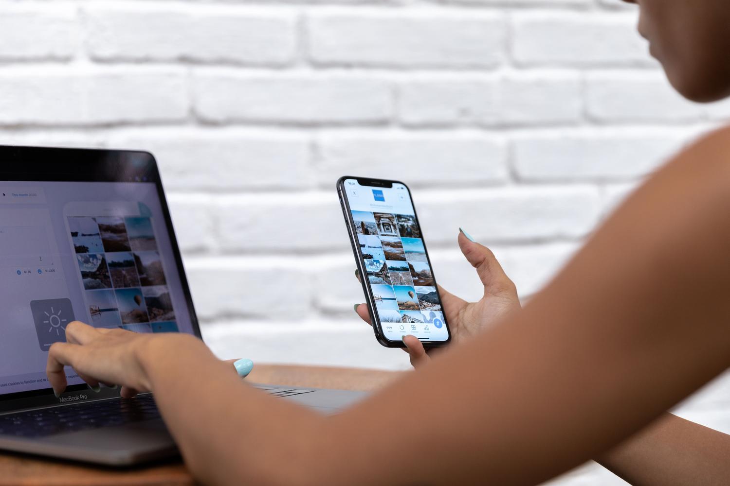 Persona trabajando en un espacio moderno con un portátil y un smartphone, ejemplificando un flujo de trabajo conectado y multiplataforma.
