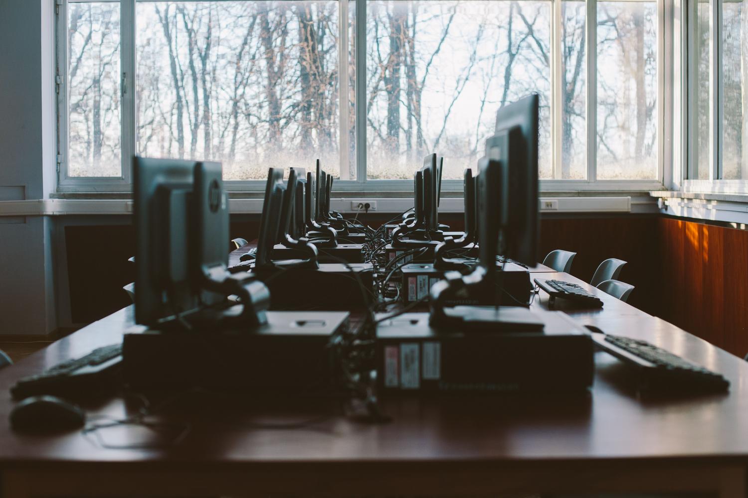 Sala de computación corporativa con múltiples estaciones de trabajo alineadas, ideal para ilustrar entornos gestionados por GPO o Intune.