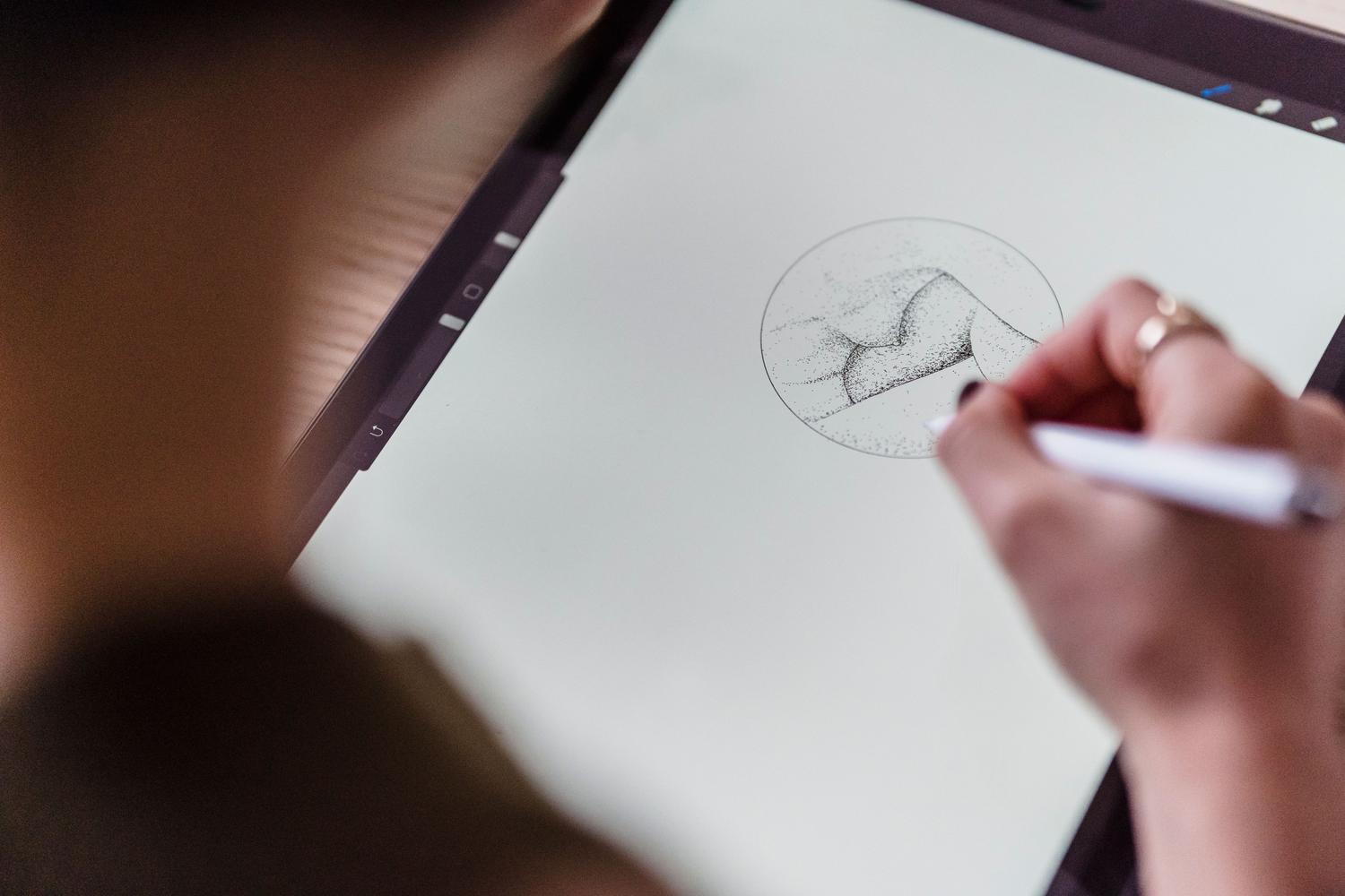 Detalle de un artista digital realizando un boceto preciso con un stylus sobre la pantalla de una tableta.