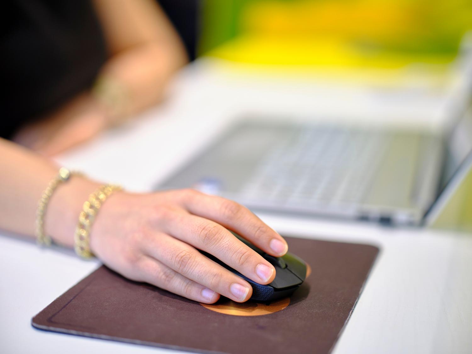 Primer plano de una persona utilizando un ratón inalámbrico sobre una alfombrilla ergonómica en un escritorio moderno. Primer plano de una persona utilizando un ratón inalámbrico sobre una alfombrilla ergonómica en un escritorio moderno.