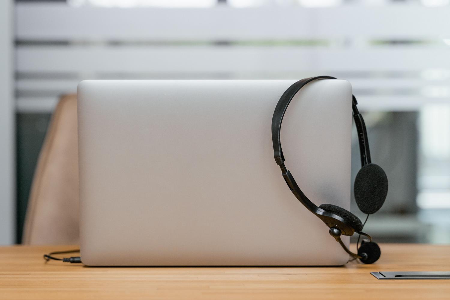 Bodegón de un ordenador portátil y unos auriculares sobre un escritorio, simbolizando las herramientas de accesibilidad y el trabajo remoto.