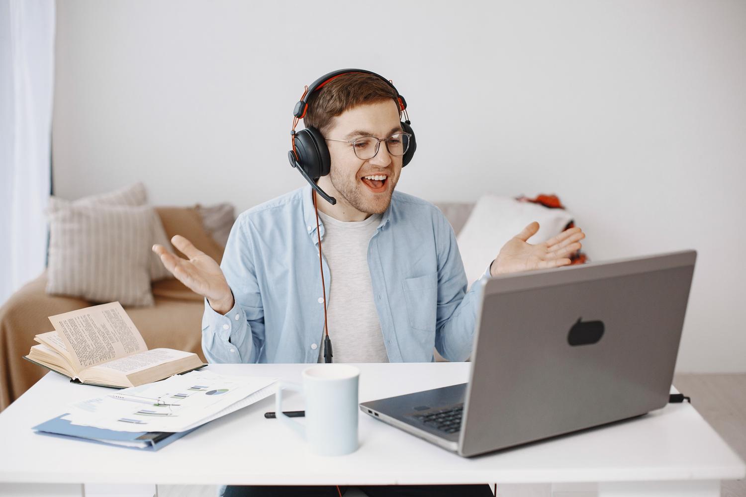 Hombre sonriente con auriculares realizando una videollamada desde su oficina en casa, representando el uso básico y nativo de la webcam en Windows 11.