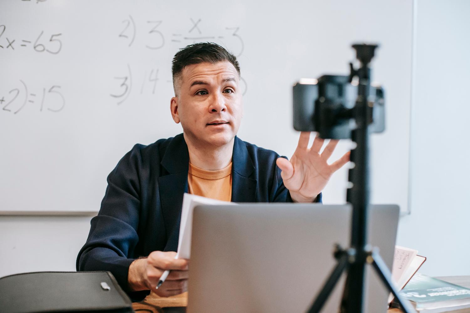 Educador profesional impartiendo una clase online con un setup de cámara y portátil, ejemplificando la optimización del hardware de video.