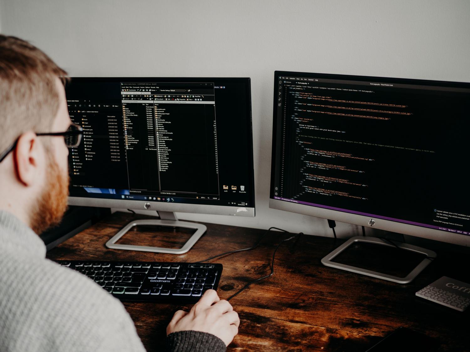 Desarrollador de software trabajando con dos pantallas en su oficina, representando un flujo de trabajo intensivo y eficiente.