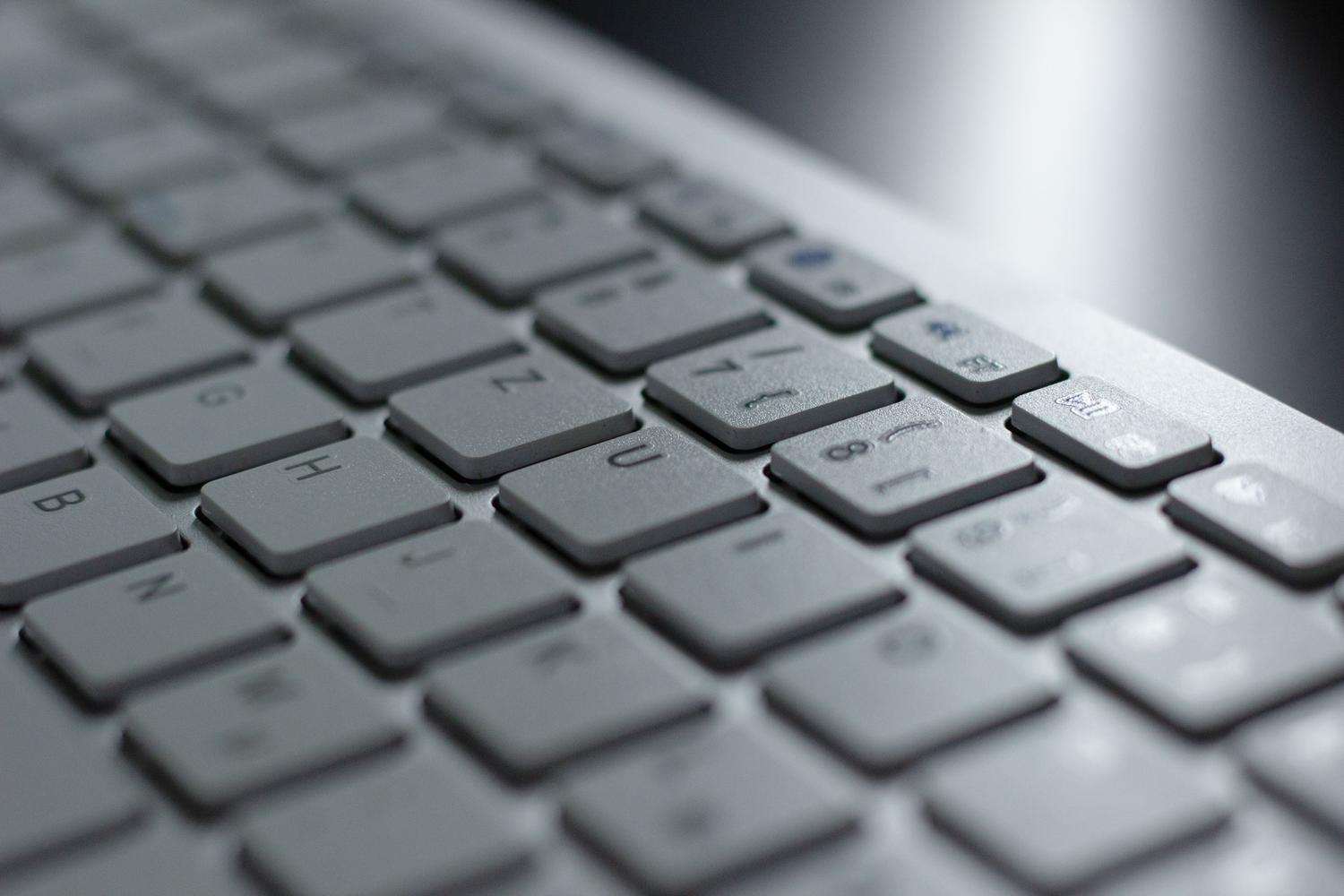 Detalle macro de un teclado de ordenador moderno con iluminación suave, resaltando el aspecto técnico y limpio del hardware.