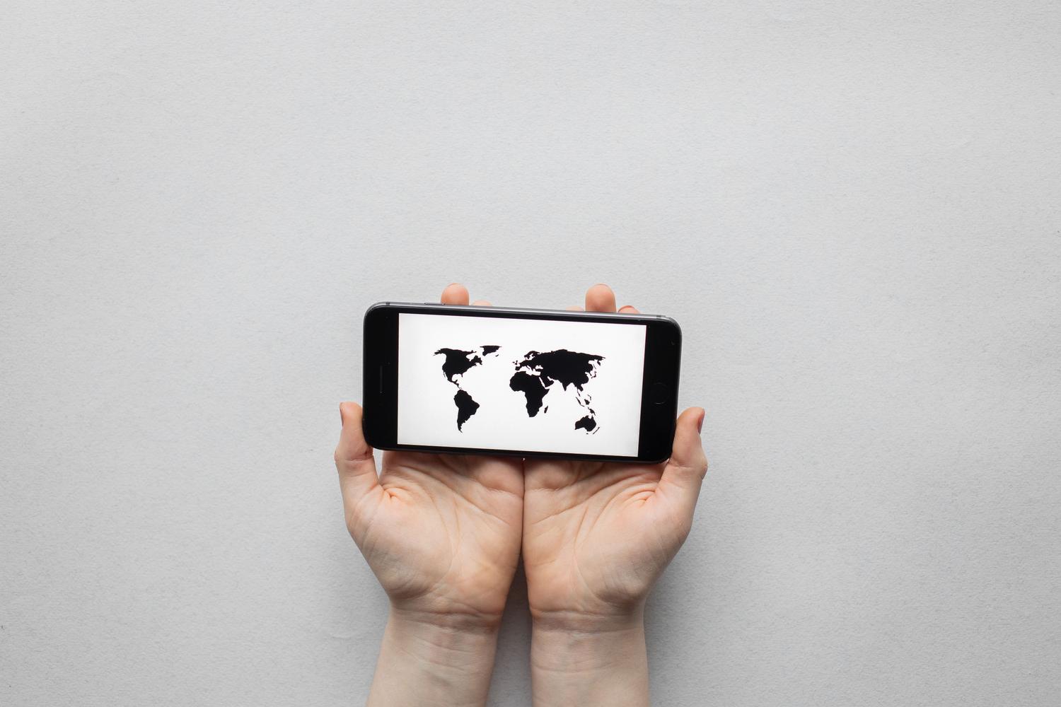 Persona sosteniendo un smartphone con un mapa mundial, representando la selección de ubicaciones para la configuración de la VPN.