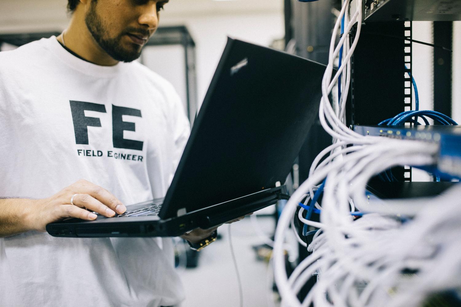 Ingeniero de redes auditando la configuración de un router mediante un ordenador portátil en un entorno de centro de datos.