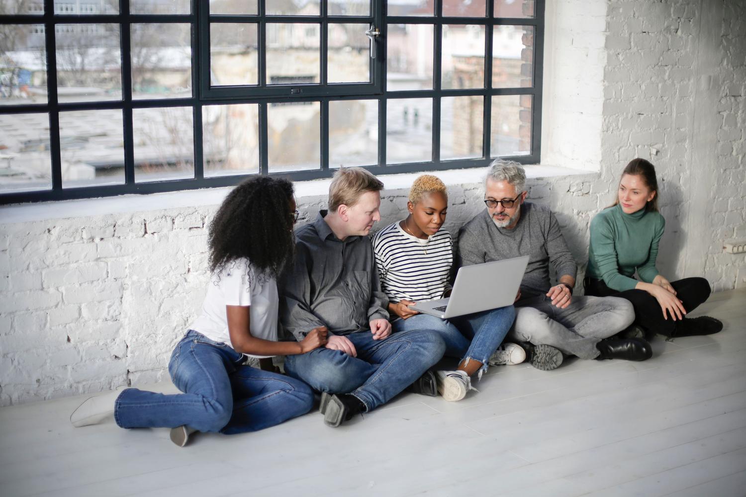 A diverse group of young people working informally with a laptop, reflecting a culture of experimentation and open collaboration. A diverse group of young people working informally with a laptop, reflecting a culture of experimentation and open collaboration.