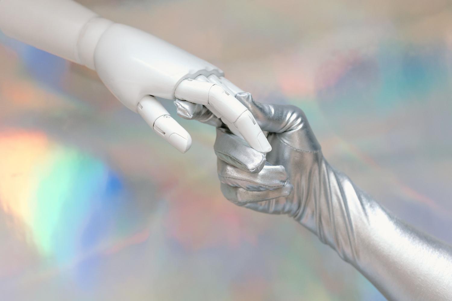 Symbolic representation of the contact between a human hand and a robotic hand, illustrating the connection and convergence between humanity and technology. Symbolic representation of the contact between a human hand and a robotic hand, illustrating the connection and convergence between humanity and technology.