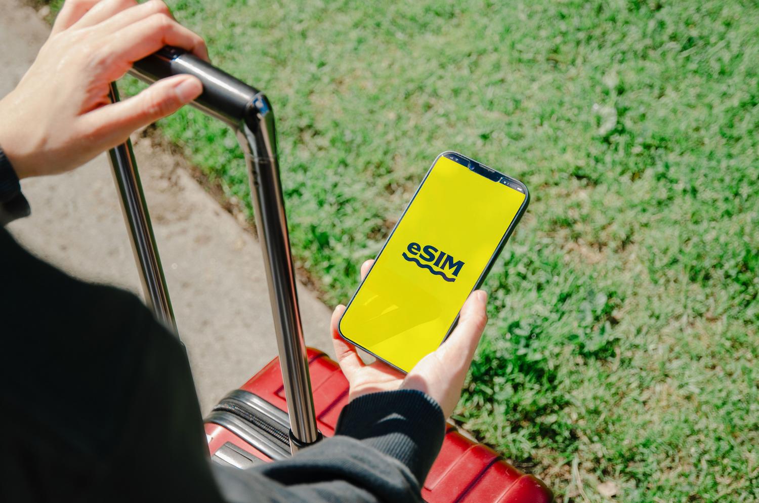 Persona sosteniendo un smartphone que muestra la configuración de una eSIM en la pantalla, representando la gestión digital de la línea.