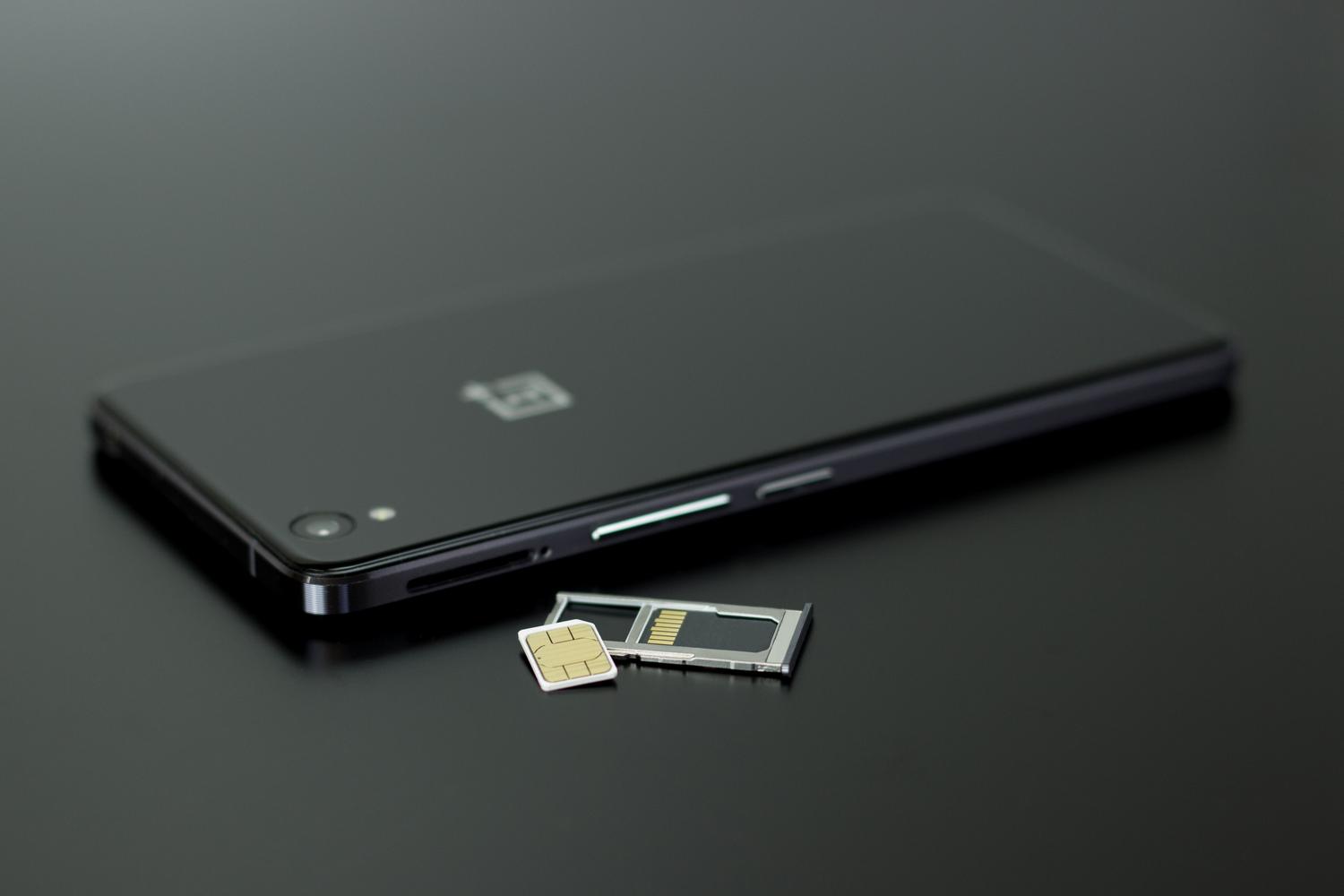 Detalle de un smartphone moderno junto a una tarjeta SIM, destacando la relación entre el dispositivo y la tarjeta de identidad.
