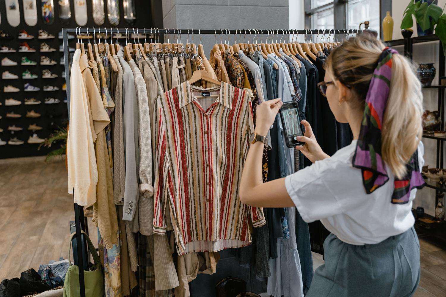 Mujer utilizando la cámara de su móvil para analizar el color y patrón de una camisa en una tienda de ropa.