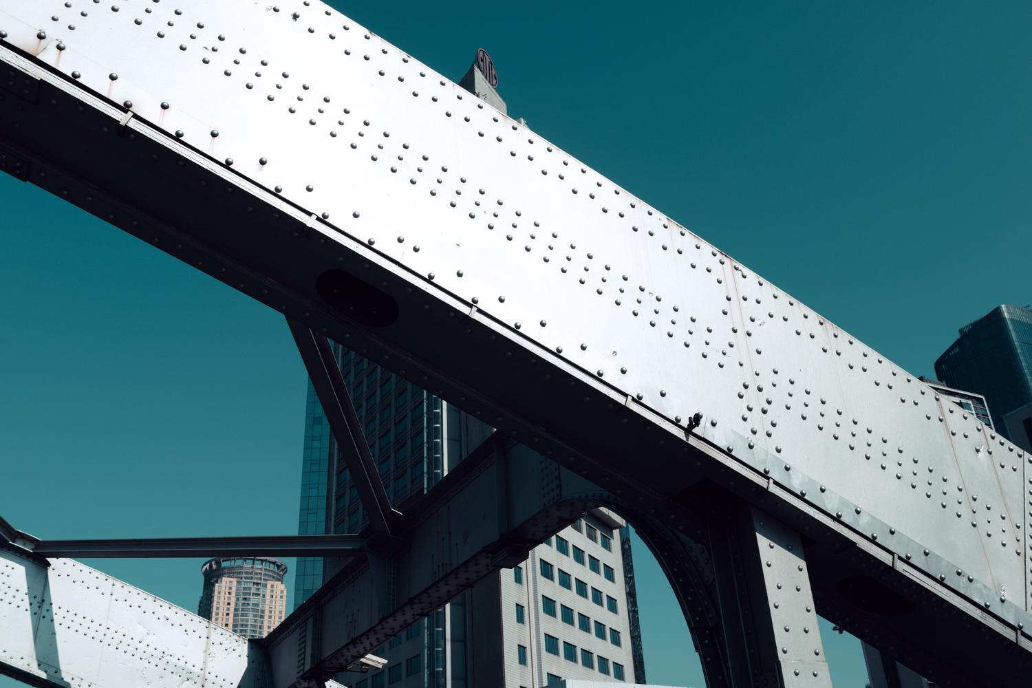 Perspectiva de la estructura de acero de un puente frente a rascacielos modernos, ejemplificando los activos urbanos que requieren SHM.