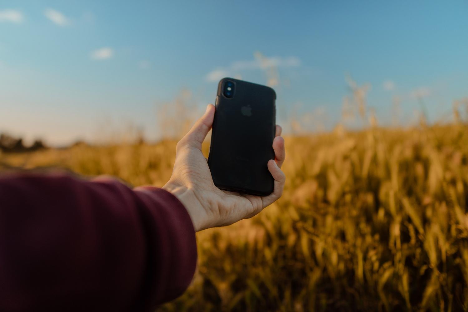 Zbliżenie na iPhone'a w naturalnym otoczeniu, symbolizujące tożsamość osobistą i personalizację urządzenia.