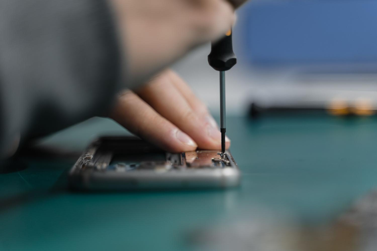 Teknik serviste akıllı telefon tamiri Teknik servis bölümü için ideal olan hassas bir tornavida kullanılarak yapılan akıllı telefon onarımının yakın çekim görüntüsü.
