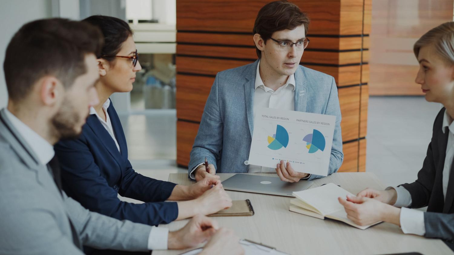 Equipo de ventas, marketing y soporte colaborando en una oficina moderna analizando datos del CRM.
