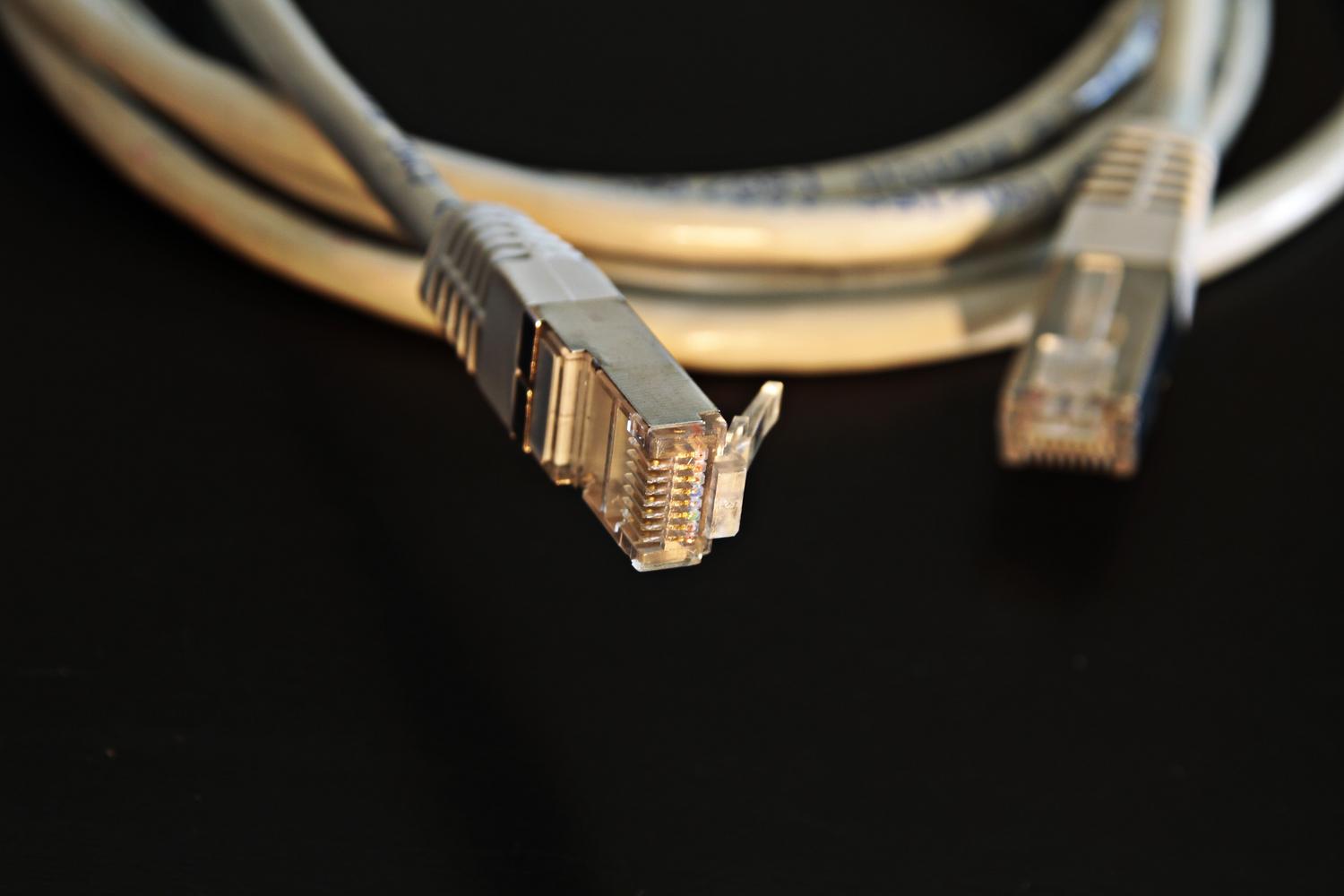 Detalizēta Ethernet kabeļa savienotāja tuvplāns, kas attēlo visefektīvāko risinājumu svārstību un latentuma samazināšanai.