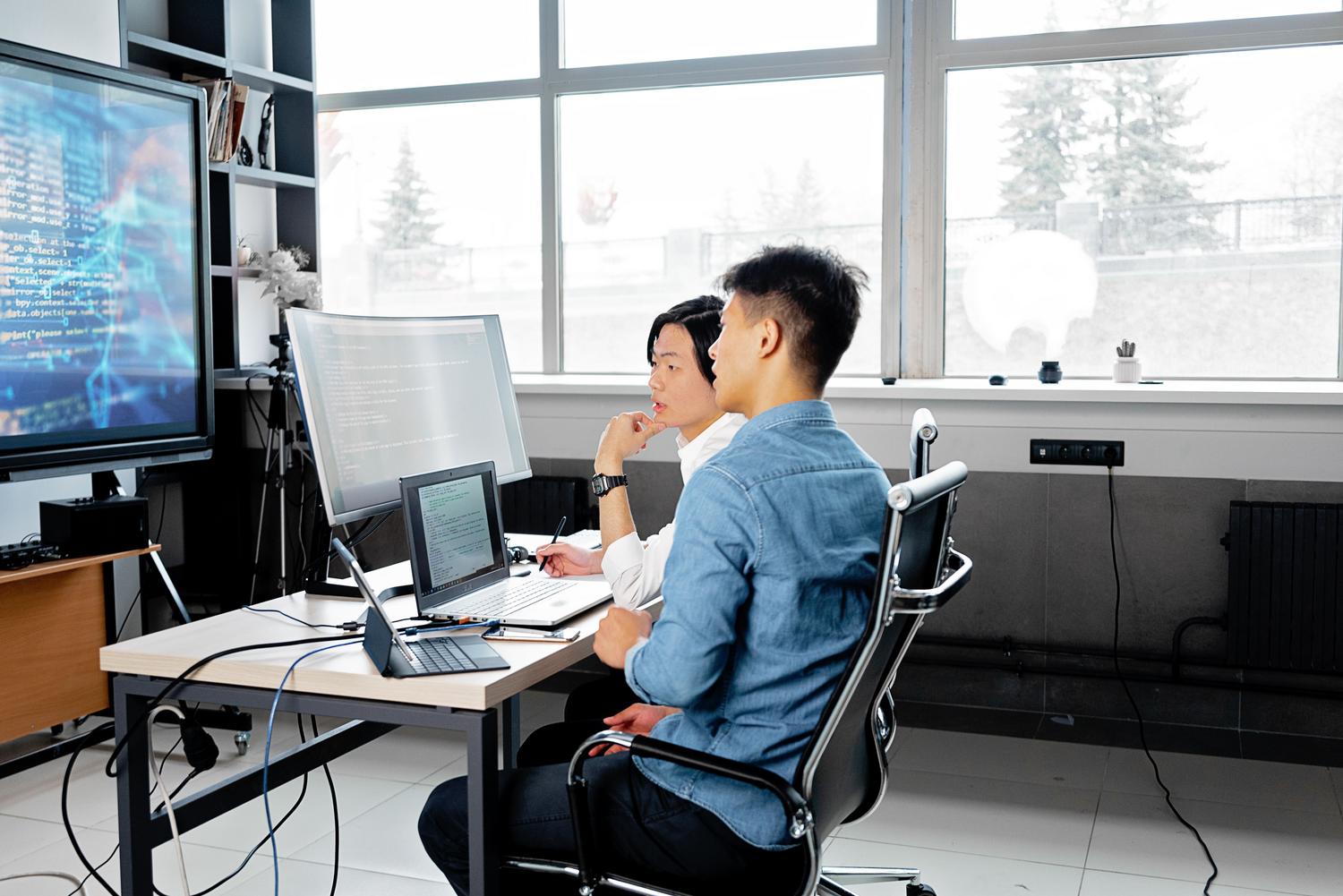 Dos desarrolladores colaborando y revisando código en un entorno de oficina, representando la importancia de la revisión humana y la responsabilidad técnica.