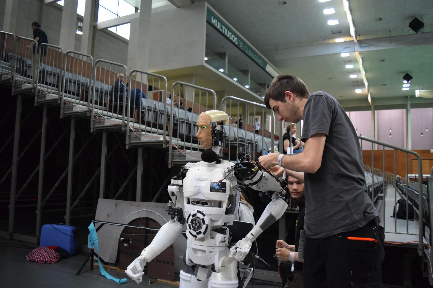 Técnico especializado ajustando un robot humanoide en una exhibición de tecnología, ilustrando la formación en robótica centrada en las personas.